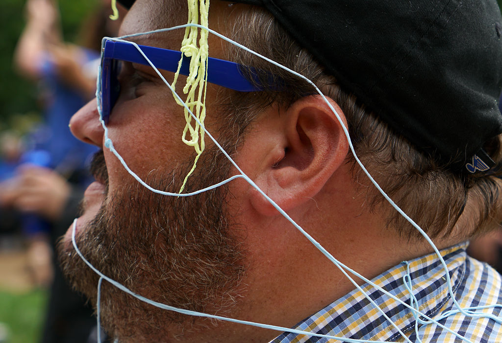 Jason Stout watches the parade, his face covered in blue and yellow Silly String